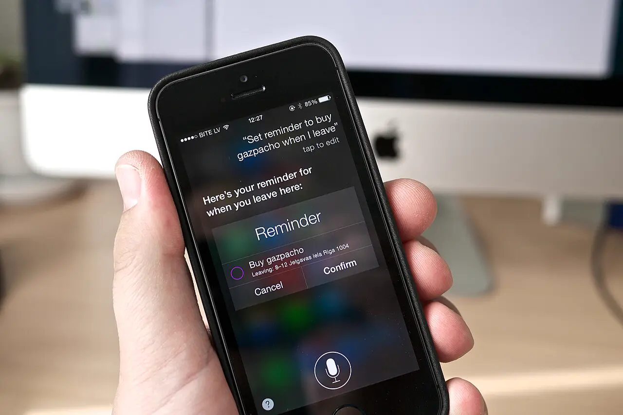 iPhone in a hand with a Siri reminder open