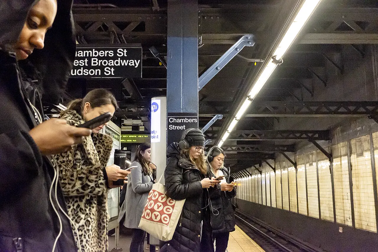 Fahrgäste mit Smartphones auf einem U-Bahnsteig