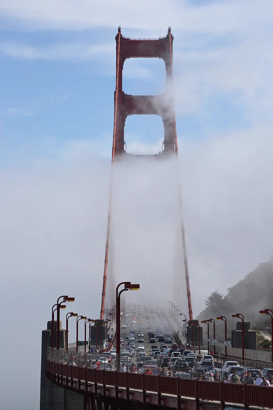 Dichter Autoverkehr auf der Golden Gate Bridge, deren Pfeiler im Nebel verschwindet.
