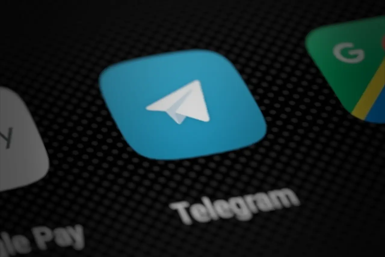Das blaue Telegram-Symbol mit Papierflieger auf einem dunklen Handybildschirm.