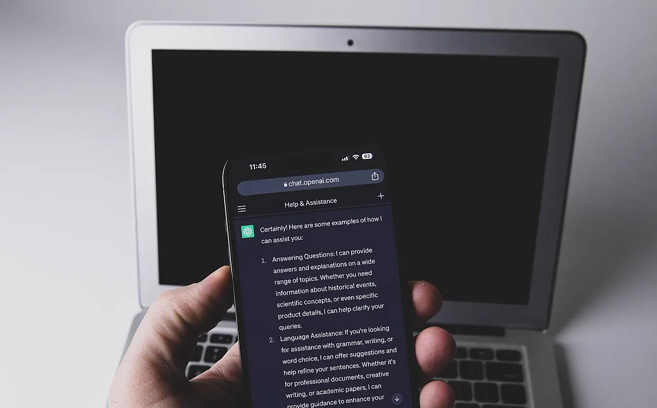 Smartphone mit ChatGPT vor einem Laptop