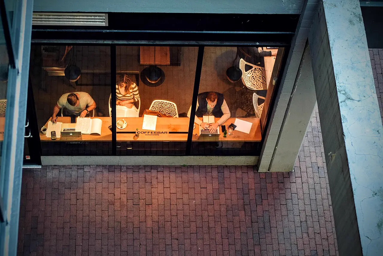 People with laptops in a café, seen from above through a window
